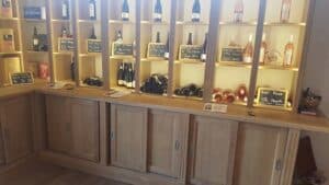 Présentoir en bois clair de cave à vin avec bouteilles de rosé AOP, étiquettes 'IGP OC Rosé' et 'AOP Rosé 5,5€/Bouteille'.