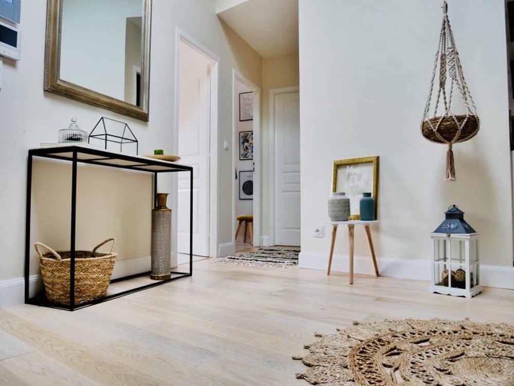 Entrée style bohème chic avec console noire, miroir doré, panier en jute et décoration murale macramé.