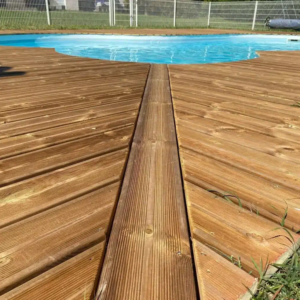Terrasse en bois autour d'une piscine, avec vue rapprochée sur les lames de bois alignées avec précision, idéale pour un espace chaleureux et fonctionnel.