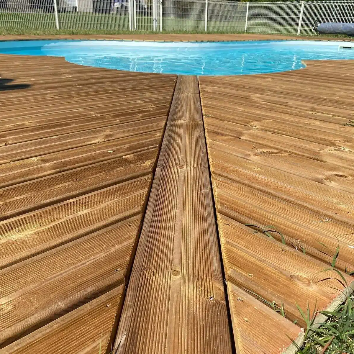 Terrasse en bois autour d'une piscine, avec vue rapprochée sur les lames de bois alignées avec précision, idéale pour un espace chaleureux et fonctionnel.