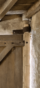 Charnière en métal rustique fixée sur une vieille porte de grange en bois et un mur en pierre.