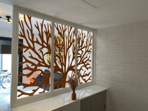 Cloison vitrée motif corail orange séparant une chambre moderne et un mur en briques blanches.