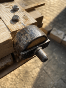 Support métal rouillé sur bois brut avec boulons hexagonaux et axe.
