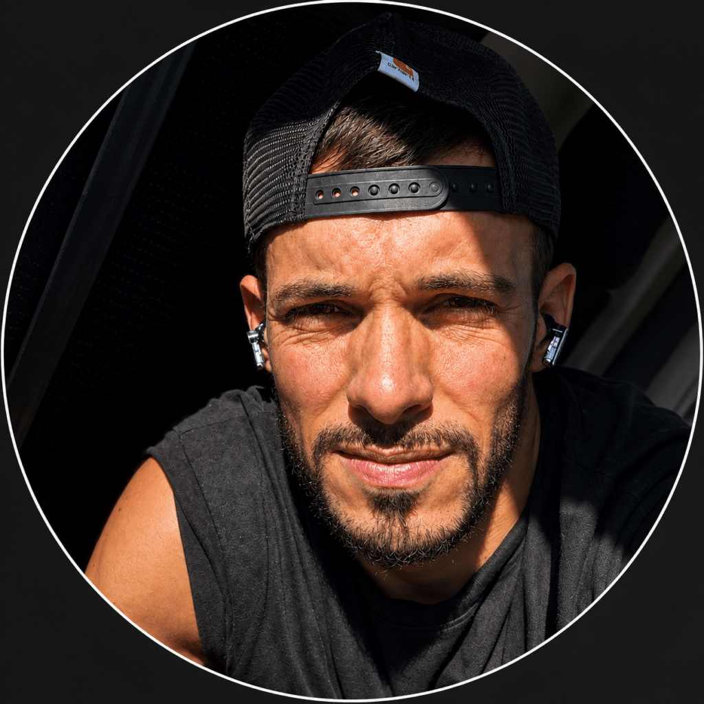 Homme Casquette Carhartt Portrait avec Écouteurs Homme barbu avec casquette Carhartt et écouteurs sans fil, éclairage contrasté.